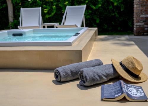 米蒂利尼奥基斯优雅小别墅酒店的热水浴池旁的一对毛巾和一顶帽子