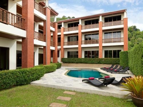 芭东海滩Sun Hill Hotel Patong的公寓大楼设有游泳池和躺椅