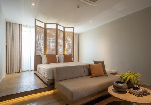 曼谷Stay Plus Hotel Bangkok的一间卧室配有一张床、一张沙发和一张桌子
