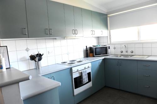 本迪戈克瑙斯度假屋的厨房配有蓝色橱柜、炉灶和微波炉。