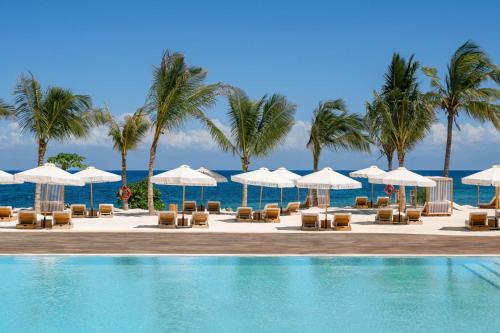 基济姆卡济Kwanza Resort by SUNRISE的一个带椅子和遮阳伞的游泳池以及大海