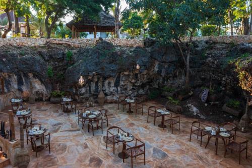 基济姆卡济Kwanza Resort by SUNRISE的石墙前设有桌椅的餐厅