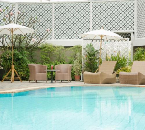 清迈兰纳宫殿2004酒店的一个带椅子和遮阳伞的游泳池