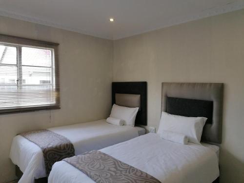 Lombardskop SettlementZithei Lodge的一间卧室设有两张床和窗户。