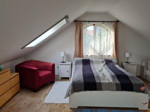 加尔多尼Duzzogó Vendégház Agárd的一间卧室配有一张床和一张红色椅子