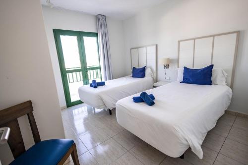 普拉亚布兰卡凯海滩太阳酒店的客房内的两张床和蓝色枕头