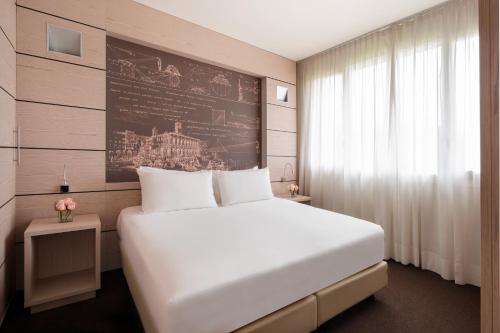 萨韦纳河畔圣拉扎罗UNAHOTELS Bologna San Lazzaro的卧室配有一张白色大床和一堵墙
