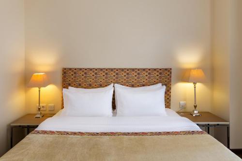 第比利斯GINGER Hotel的一间卧室配有一张带两盏灯的大型白色床。