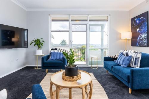 悉尼Mosman Views, 2bed, Parking, 15min Walk to Beach的客厅配有蓝色的沙发和桌子