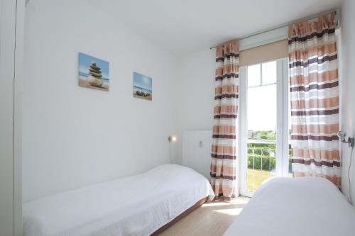 博尔滕哈根Achtern Diek Wohnung 14的一间卧室设有两张床和窗户。