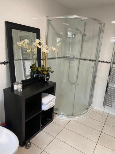 欣克利Hansom House的带淋浴的浴室和带鲜花的黑色柜台。