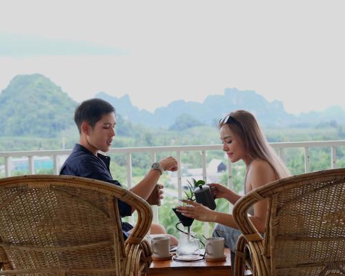 奥南海滩Baan Phuvara Retreat - Romantic Jacuzzi Mountain View Villas的坐在桌子上的男人和女人