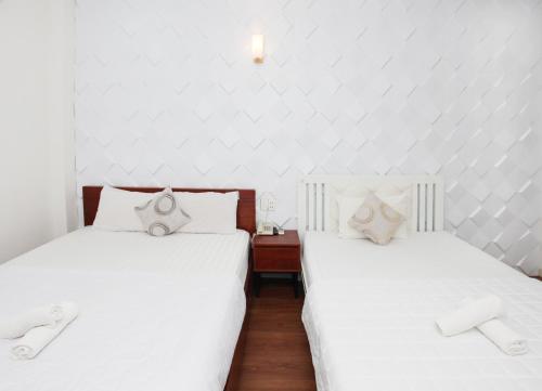 胡志明市Nguyen Thanh Hotel的配有2张床铺、白色床单和拖鞋的客房