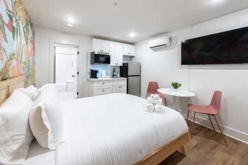 加尔维斯敦Pastel Tropics Studio Apartment的白色的卧室配有白色的床和一张桌子