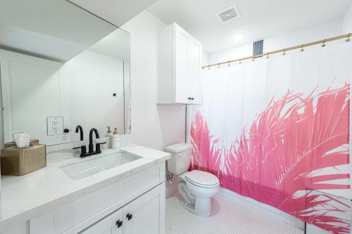 加尔维斯敦Pastel Tropics Studio Apartment的一间带卫生间的浴室和粉红色的壁纸