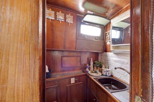 阿拉西奥Aloha Jak's Boat的厨房配有木制橱柜、水槽和窗户。