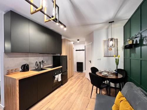 卡托维兹Green Hill Apartments Katowice的一间厨房,内设黑色橱柜和一张桌子