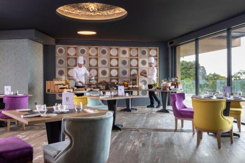 韦基奥圣露西港口Les Regalia Hôtel & Spa的餐厅设有桌椅,厨师为背景