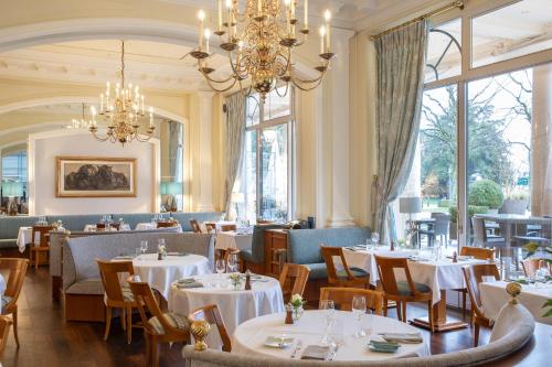洛桑洛桑美岸皇宫大酒店的一间带桌椅和吊灯的餐厅