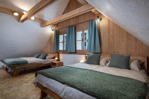 Nižná BocaChalupa Bocza的配有木墙和蓝色窗帘的客房内的两张床