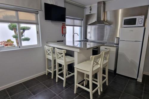 埃斯平霍Casa de Férias_As Oliveiras I的厨房配有带凳子的柜台和冰箱。