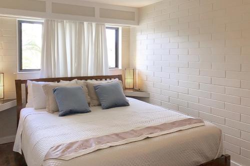 科洛阿Kuhio Shores 201的白色卧室配有一张带蓝色枕头的大床