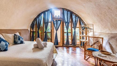 科洛尼亚-德尔萨克拉门托Caliu Earthship Ecolodge的一间卧室设有一张床和一个大窗户