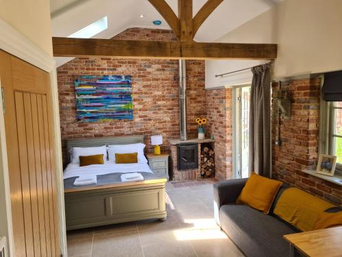 基督城Dragonfly cottage的一间卧室配有床、沙发和砖墙