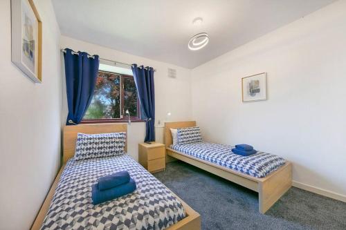 阿伯丁Faulds Crescent Lodge ✪ Grampian Lettings Ltd的一间卧室设有两张床,窗户配有蓝色窗帘