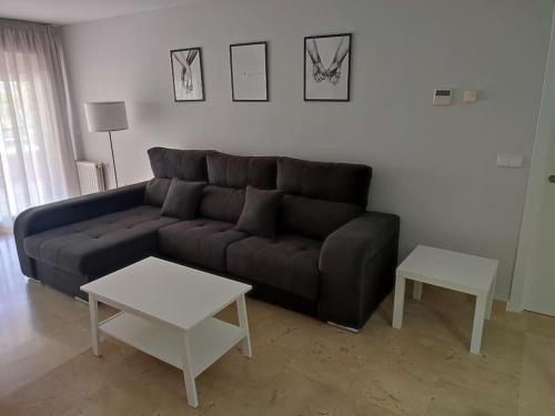 马贝拉Sunny Guadalmina Apartment的客厅配有黑色沙发和2张桌子