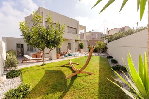 PrasásArte Casa Luxury Resort的坐在房子前面草坪上的木椅
