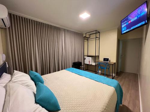 巴西利亚Hotel Suntuoso的配有一张床和一台平面电视的酒店客房