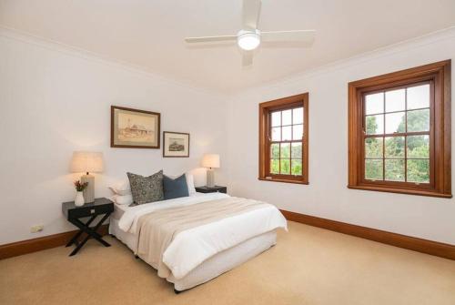 汉道夫Hahndorf Luxury Retreat的一间白色卧室,配有床和2个窗户