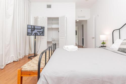 迈阿密Miami Downtown 2 Bedrooms Apartment - 10 minutes to Beach - 5 minutes to Wynwood的白色卧室设有一张大床和电视。