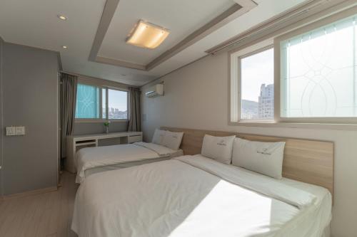釜山Staywell Hotel的带2扇窗户的客房内的2张床