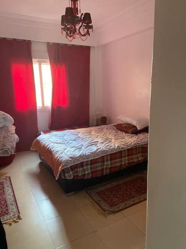 马拉喀什appartement dans résidence Marrakech avec piscine的一间卧室配有一张带红色窗帘的床和一扇窗户