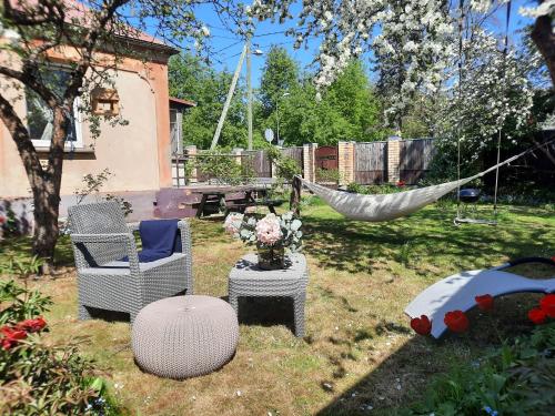 里加Cozy private house with a yard & parking的庭院内的吊床,配有椅子和桌子