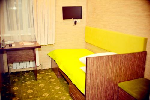 奇姆肯特Sapar Budget Hotel的小房间设有黄色的床和书桌