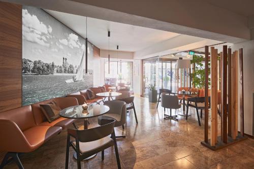 腓特烈港科隆市酒店的餐厅设有桌椅,墙上挂有绘画作品