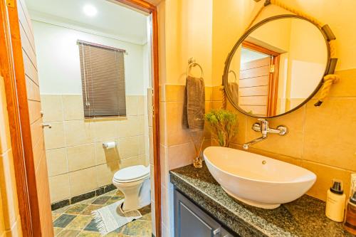 马布拉Kubu Lodge的一间带水槽、卫生间和镜子的浴室