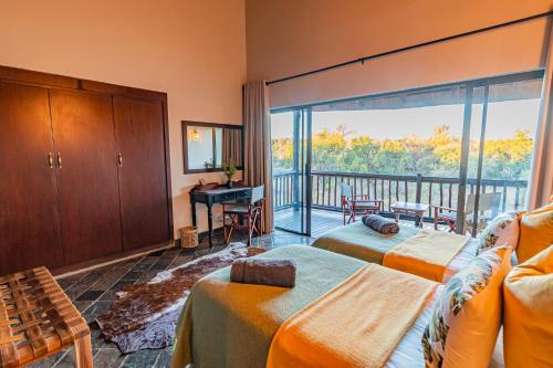 马布拉Kubu Lodge的一间带两张床的卧室和一个阳台