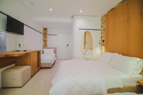 萨兰达Hotel Piccolino的卧室配有一张白色大床和一张书桌