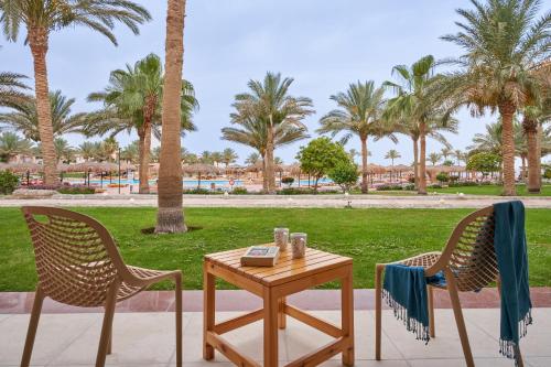 考拉亚湾Three Corners Sea Beach Resort的桌子和两把椅子,配有桌子和棕榈树
