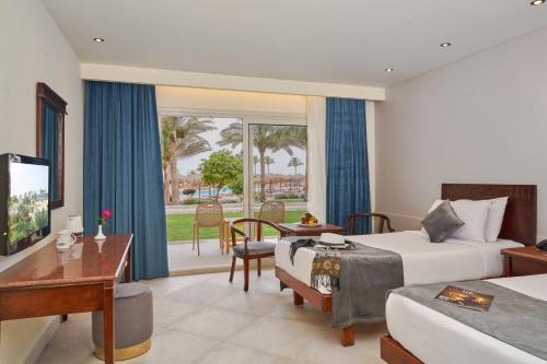 考拉亚湾Three Corners Sea Beach Resort的酒店客房设有两张床、一张桌子和一张桌子。