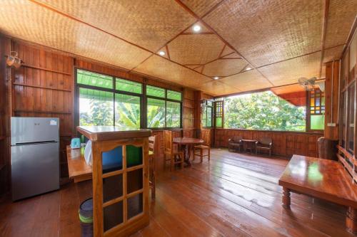 南邦Kanecha's Home Lampang的大型客房,铺有木地板,设有桌子和窗户。