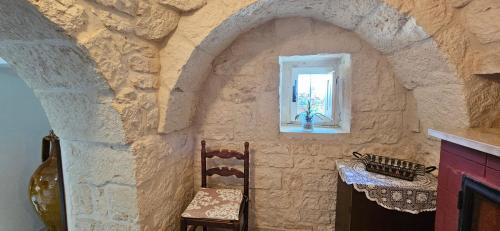 洛科罗通多Trulli Giovanni e Angela的一间设有石墙、两把椅子和一扇窗户的房间