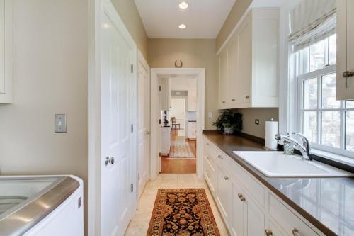 温泉城Homestead Lookout的厨房配有白色橱柜、水槽和窗户。