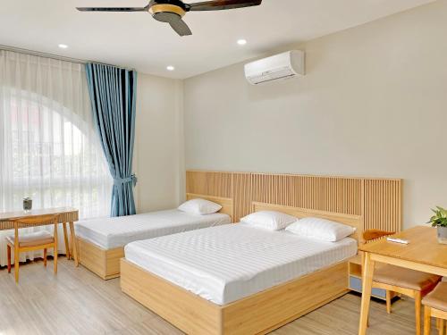 岘港Moc Son Apartment - Attractive price for week and month stay的一间卧室配有两张床、一张桌子和一张书桌