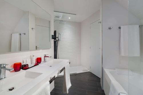 凯恩Best Western Plus Le Moderne的白色的浴室设有2个盥洗盆和淋浴。