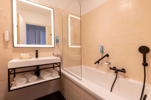 圣马克西姆Best Western Hotel Matisse的一间带水槽、浴缸和镜子的浴室